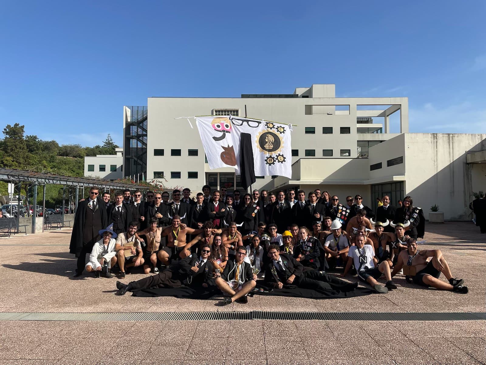 Estudantes de Engenharias e Matemática reunidos no campus com a bandeira da praxe